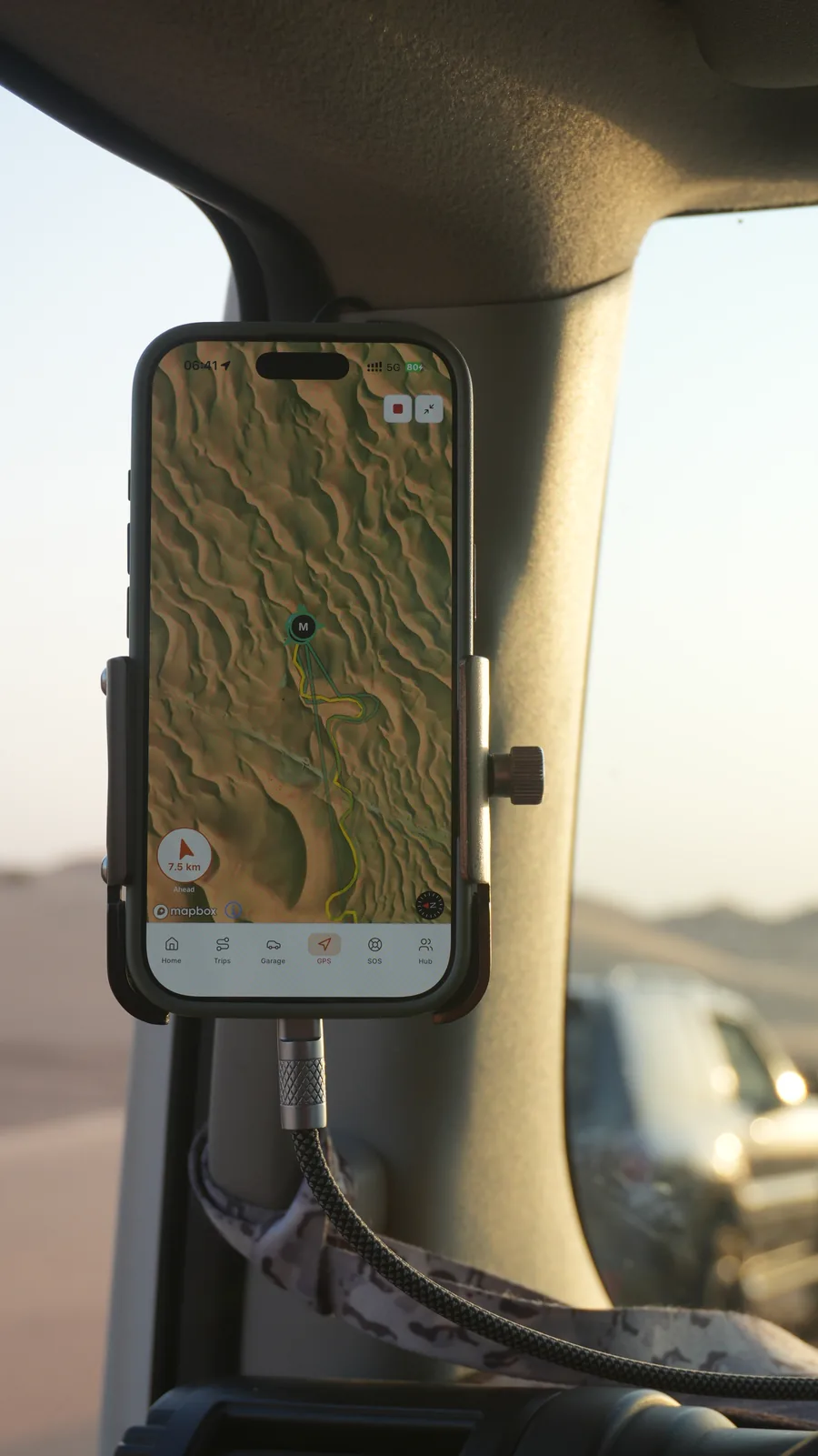 Close-up of a mounted phone displaying desert terrain and a track line in Navra