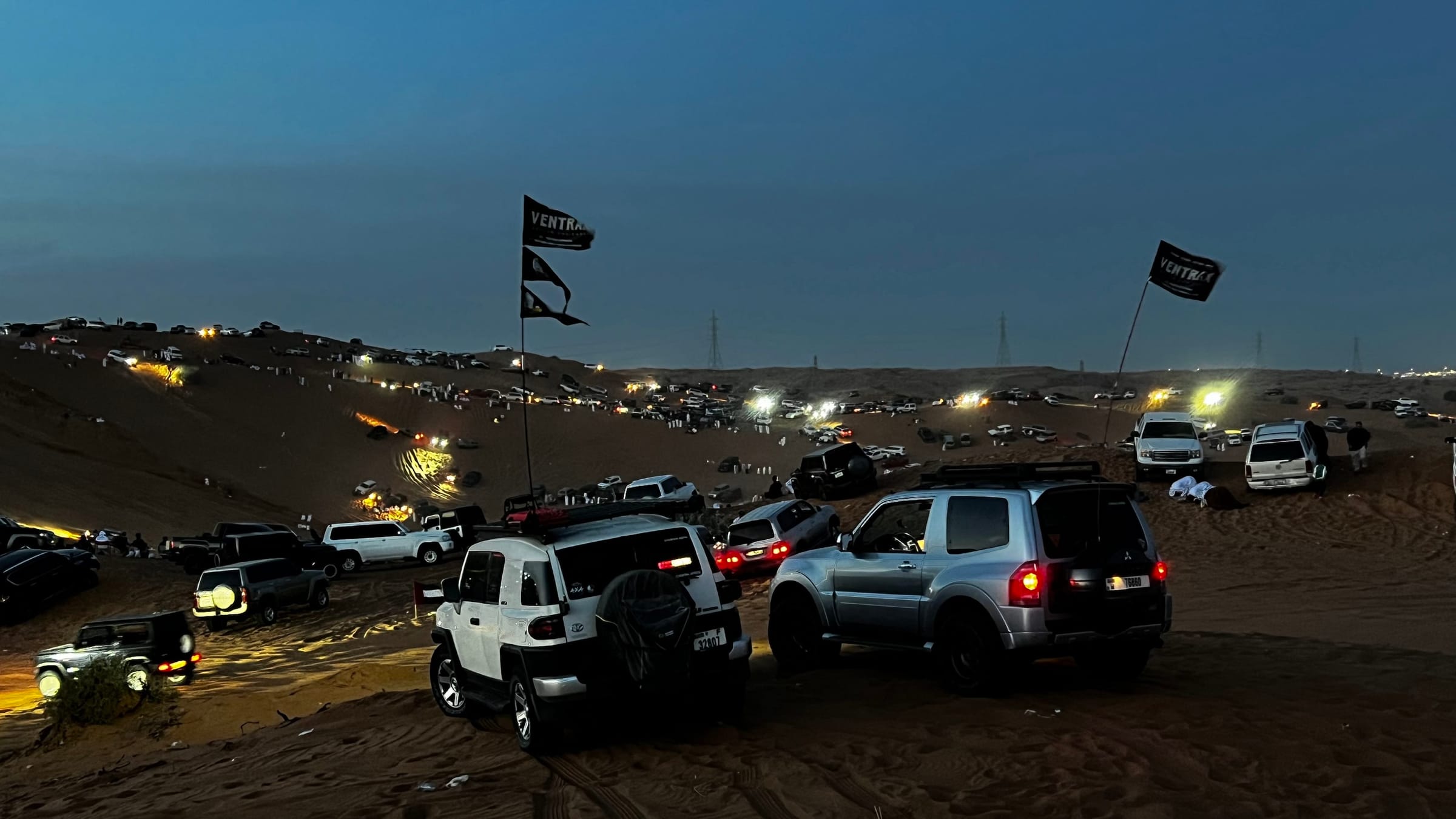 Ventrax Offroad night drive event with 4x4 vehicles and branded flags in the UAE desert